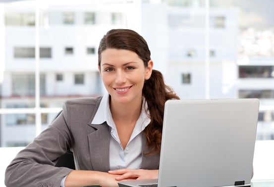 Smiling woman on the computer looking at the camera in her office