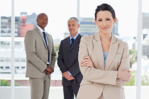 Young smiling secretary crossing her arms in front of two executives